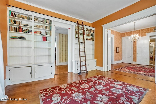 entrance foyer featuring hardwood / wood-style flooring, crown molding, and an inviting chandelier