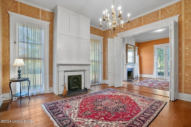 living room with crown molding, wood-type flooring, and a chandelier