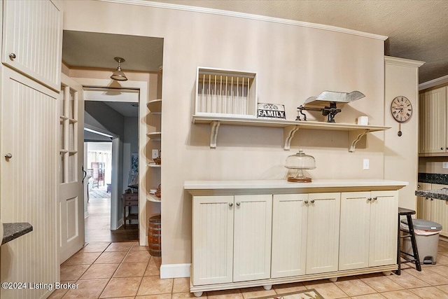 kitchen featuring crown molding, light tile patterned floors, and a textured ceiling