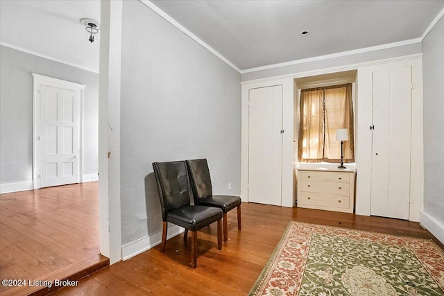 living area with ornamental molding, vaulted ceiling, and wood-type flooring