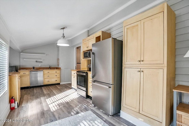 kitchen featuring pendant lighting, appliances with stainless steel finishes, wood-type flooring, ornamental molding, and light brown cabinetry