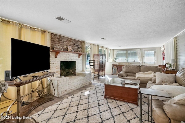 living room with a fireplace, light hardwood / wood-style flooring, and a textured ceiling