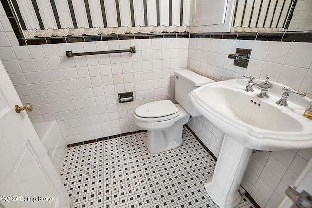 bathroom with sink, tile walls, a bathtub, tile patterned flooring, and toilet