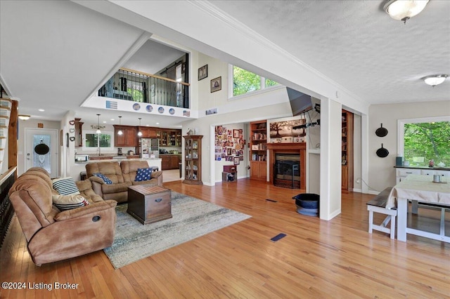 living room with light wood-type flooring, a textured ceiling, and a high ceiling