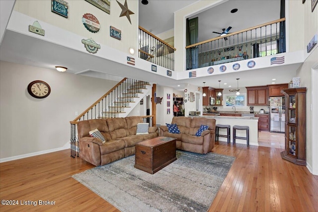 living room featuring ceiling fan, light hardwood / wood-style flooring, and a high ceiling