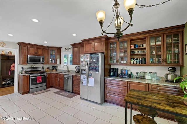 kitchen with light stone counters, light tile patterned floors, stainless steel appliances, and hanging light fixtures