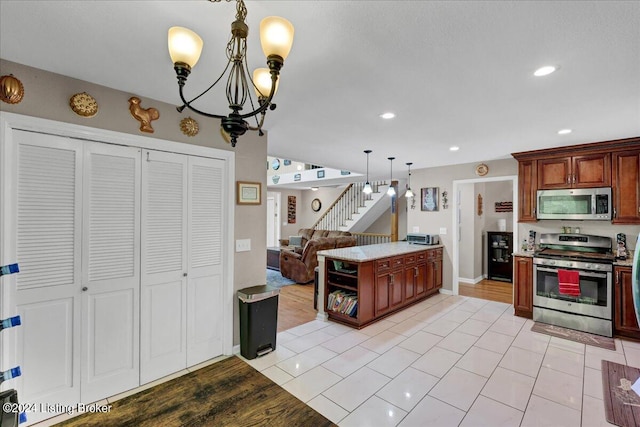 kitchen with a notable chandelier, light wood-type flooring, stainless steel appliances, and pendant lighting