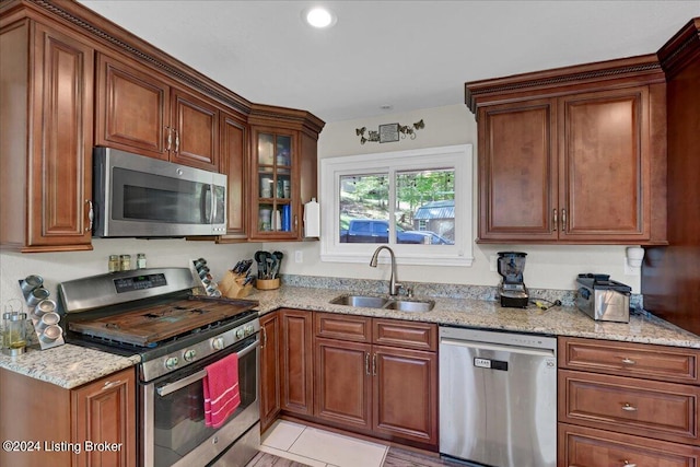 kitchen with light stone counters, appliances with stainless steel finishes, sink, and light tile patterned floors