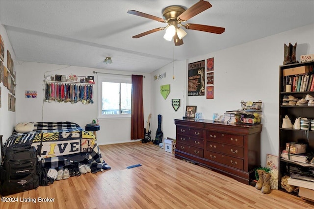 interior space featuring ceiling fan, light wood-type flooring, a textured ceiling, and vaulted ceiling