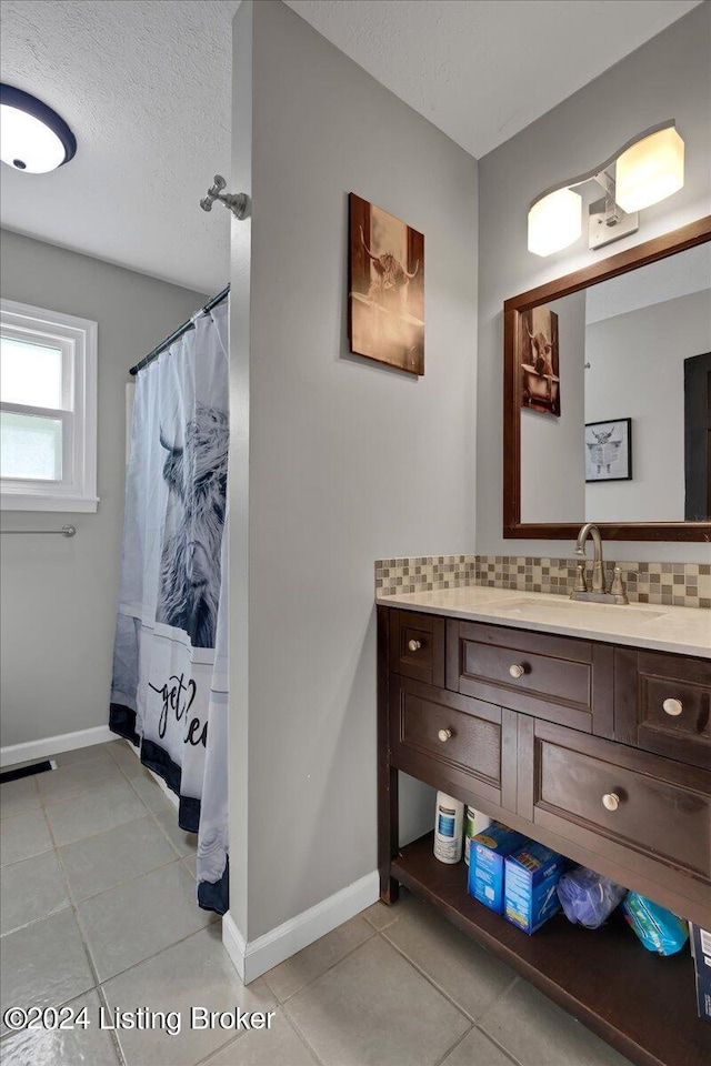 bathroom featuring decorative backsplash, a textured ceiling, tile patterned floors, and vanity