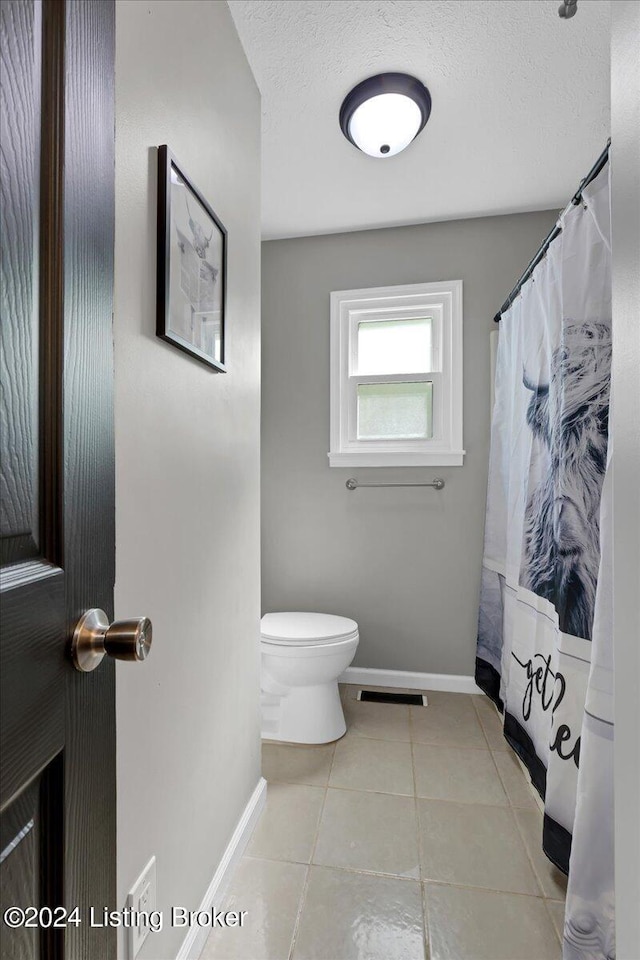 bathroom with a textured ceiling, tile patterned floors, and toilet