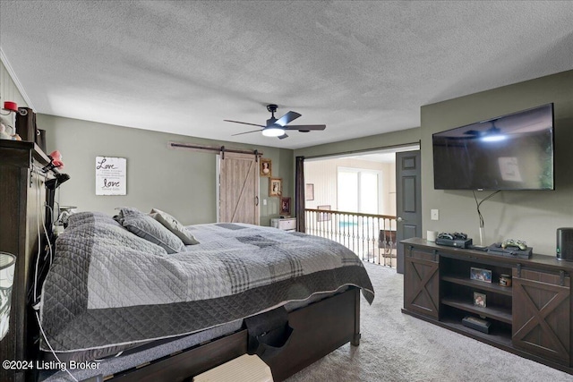 carpeted bedroom featuring ceiling fan, a barn door, and a textured ceiling