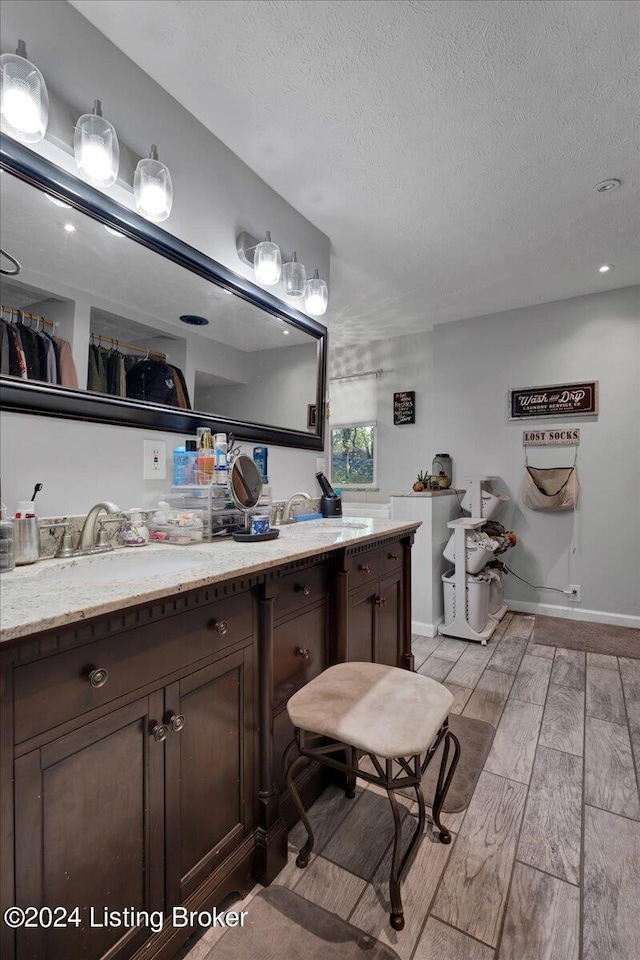 bathroom with a textured ceiling, vanity, and hardwood / wood-style flooring