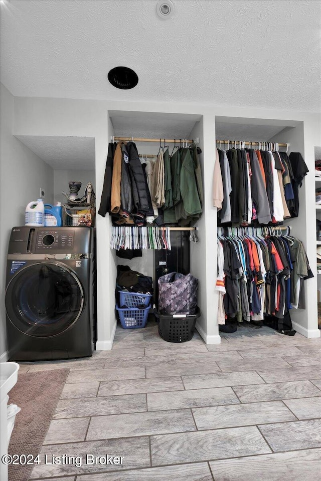 clothes washing area featuring washer / dryer and a textured ceiling