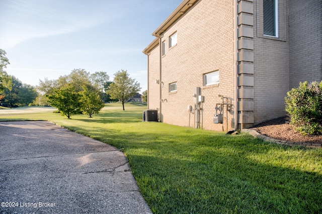 view of side of home with central AC unit and a lawn