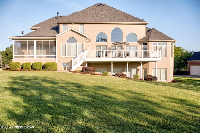 rear view of property featuring a garage, a sunroom, and a lawn