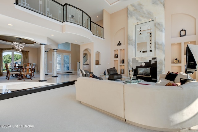 living room featuring ornate columns, a high ceiling, built in features, a fireplace, and french doors