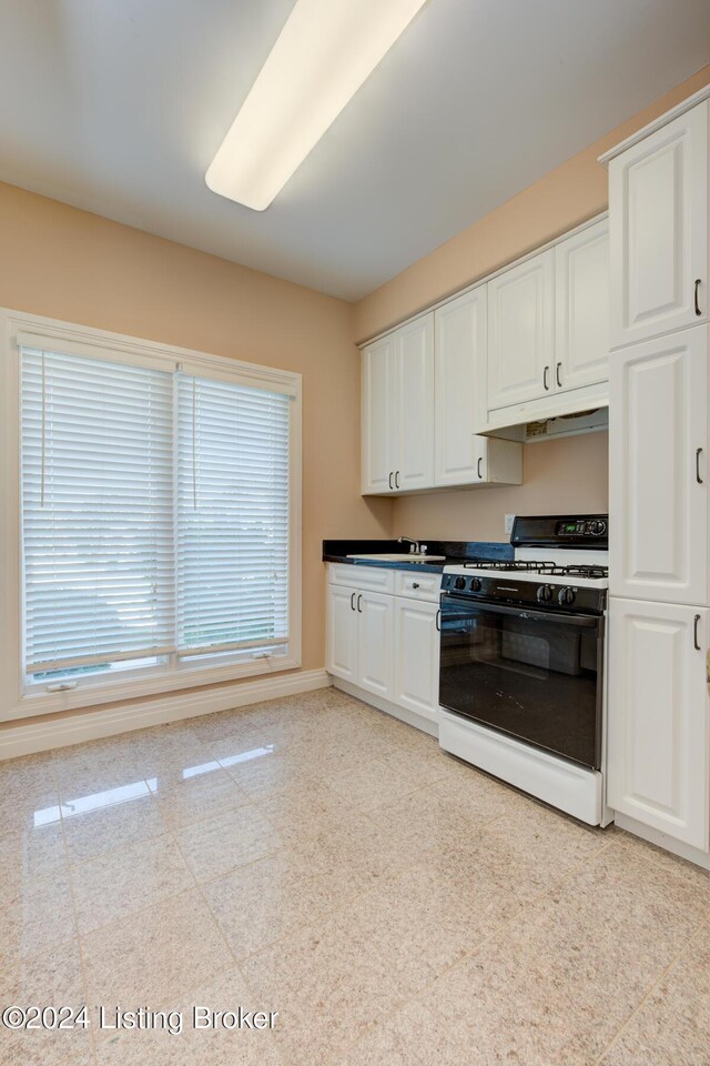 kitchen featuring sink, white cabinets, light tile patterned floors, and white range with gas cooktop