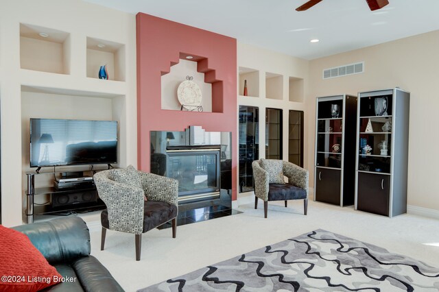 living room featuring ceiling fan, built in shelves, and carpet floors