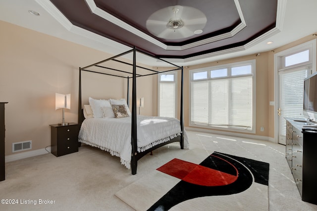 carpeted bedroom featuring a tray ceiling, ceiling fan, and crown molding