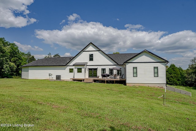 back of property with central air condition unit, roof with shingles, a deck, and a yard