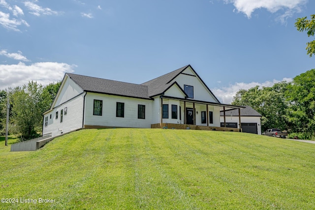 modern farmhouse featuring a garage, a porch, a shingled roof, and a front lawn