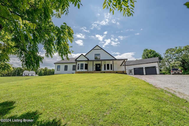 modern inspired farmhouse featuring an attached garage, covered porch, a front lawn, and gravel driveway