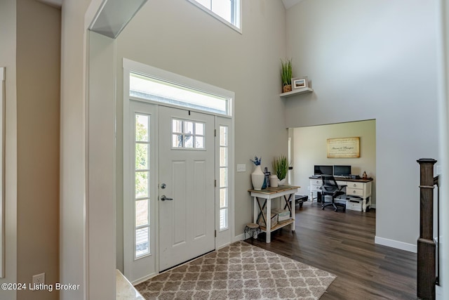 foyer with dark wood-style floors, a high ceiling, and baseboards