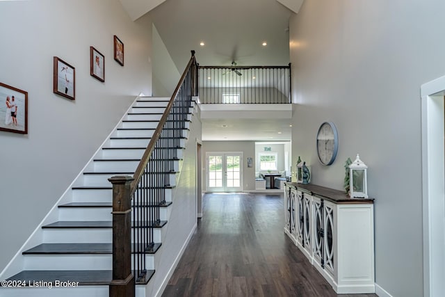 stairway with baseboards, a towering ceiling, wood finished floors, french doors, and recessed lighting