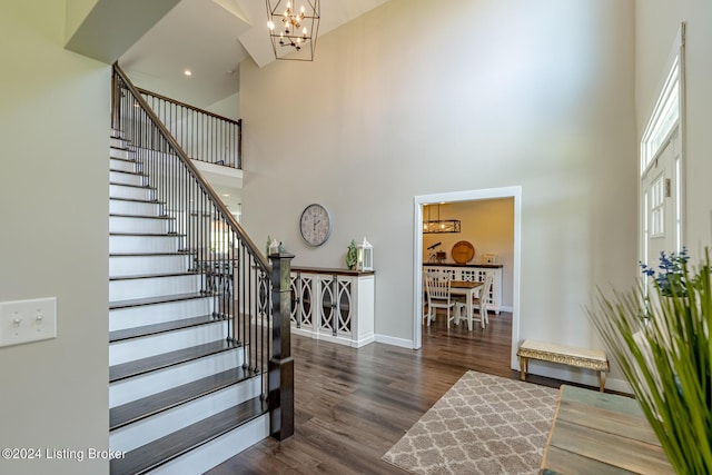 staircase featuring baseboards, a high ceiling, a chandelier, and wood finished floors