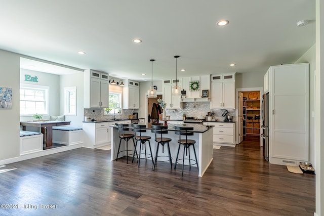 kitchen featuring a center island, decorative light fixtures, dark countertops, glass insert cabinets, and white cabinetry