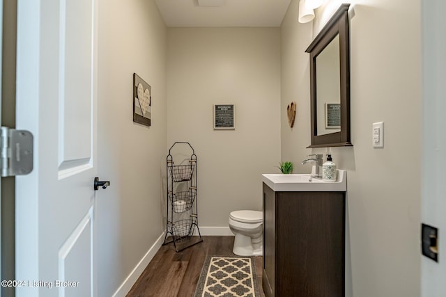 bathroom with toilet, baseboards, wood finished floors, and vanity