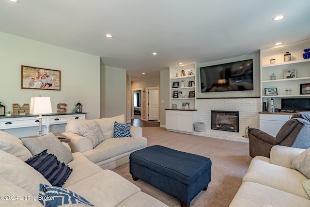 living room with a brick fireplace, built in features, light colored carpet, and recessed lighting