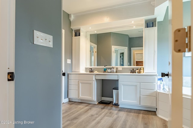 full bath with double vanity, a sink, and wood finished floors