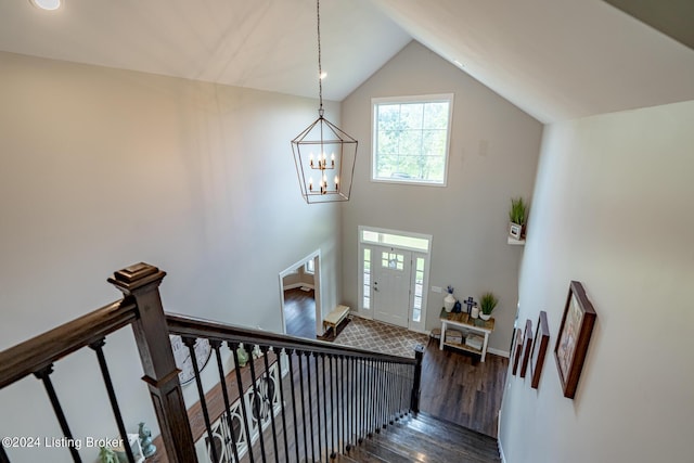 stairs featuring lofted ceiling, wood finished floors, and a chandelier