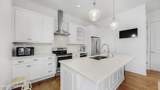 kitchen with pendant lighting, white cabinetry, stainless steel appliances, wall chimney exhaust hood, and a center island with sink