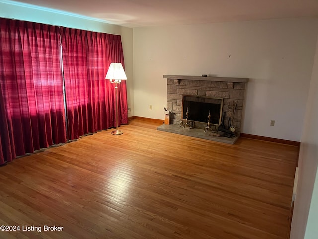 unfurnished living room featuring a stone fireplace and wood-type flooring