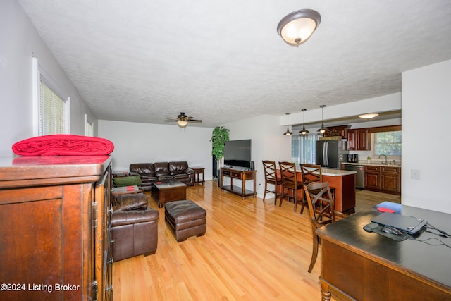 living room featuring ceiling fan, a textured ceiling, light hardwood / wood-style flooring, and sink