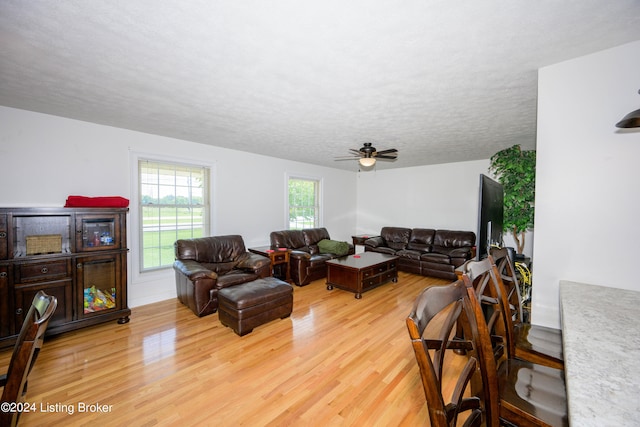 living room with ceiling fan, a textured ceiling, and light hardwood / wood-style floors