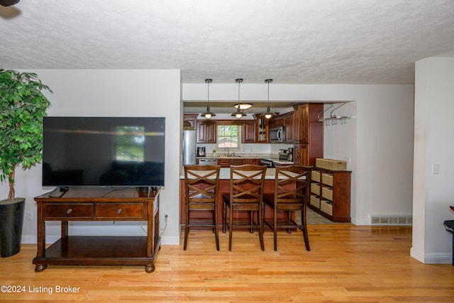 dining area featuring sink, light hardwood / wood-style flooring, and a textured ceiling