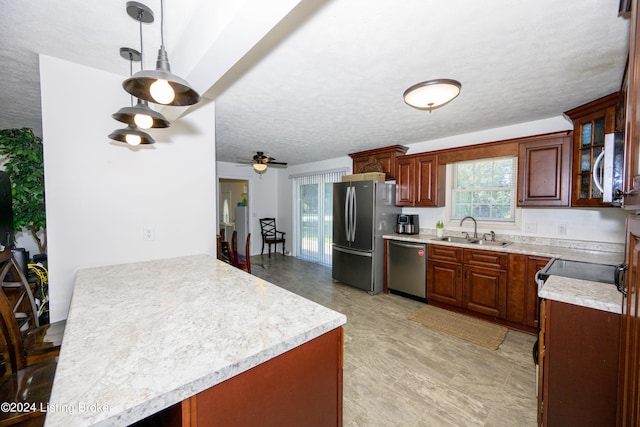 kitchen with appliances with stainless steel finishes, decorative light fixtures, ceiling fan, and sink