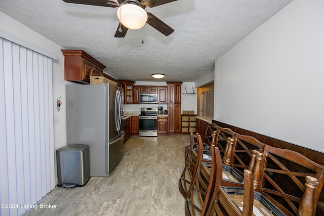 kitchen with ceiling fan, a textured ceiling, and stainless steel appliances