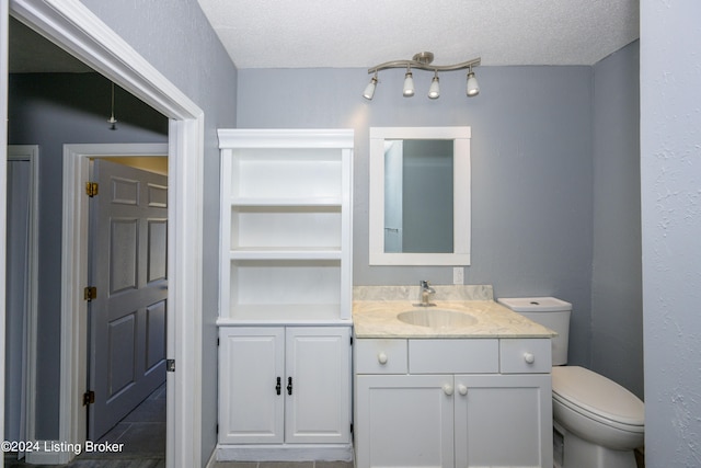 bathroom featuring a textured ceiling, vanity, and toilet