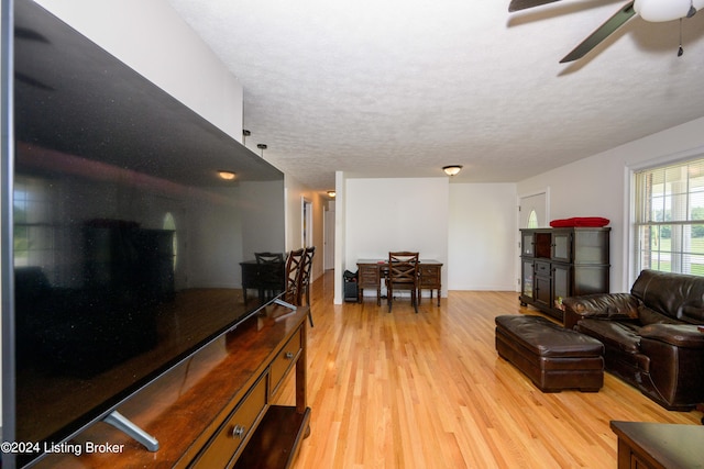 living room featuring a textured ceiling, light hardwood / wood-style flooring, and ceiling fan