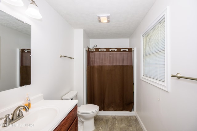 bathroom with a textured ceiling, vanity, and toilet