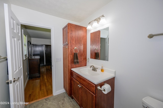 bathroom with toilet, vanity, and wood-type flooring