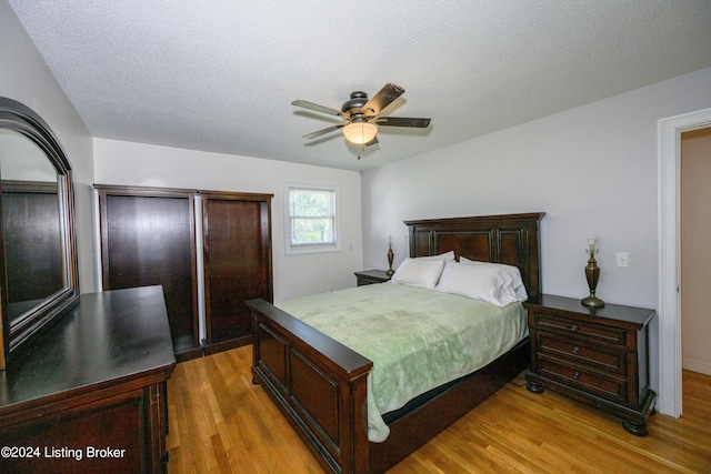 bedroom with ceiling fan, a closet, light hardwood / wood-style floors, and a textured ceiling