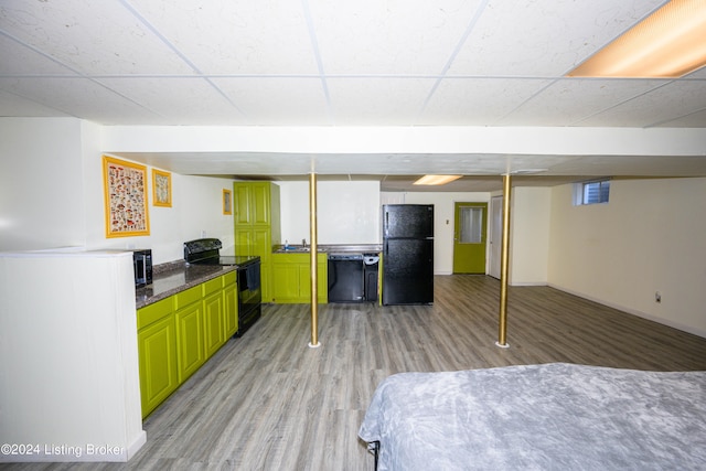 kitchen featuring light wood-type flooring, a drop ceiling, green cabinetry, and black appliances