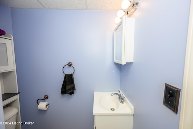 bathroom with a paneled ceiling, toilet, and vanity