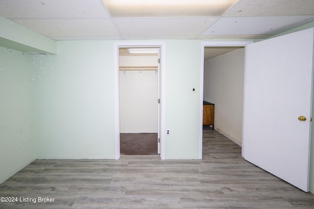 unfurnished bedroom with a walk in closet, a paneled ceiling, and hardwood / wood-style flooring